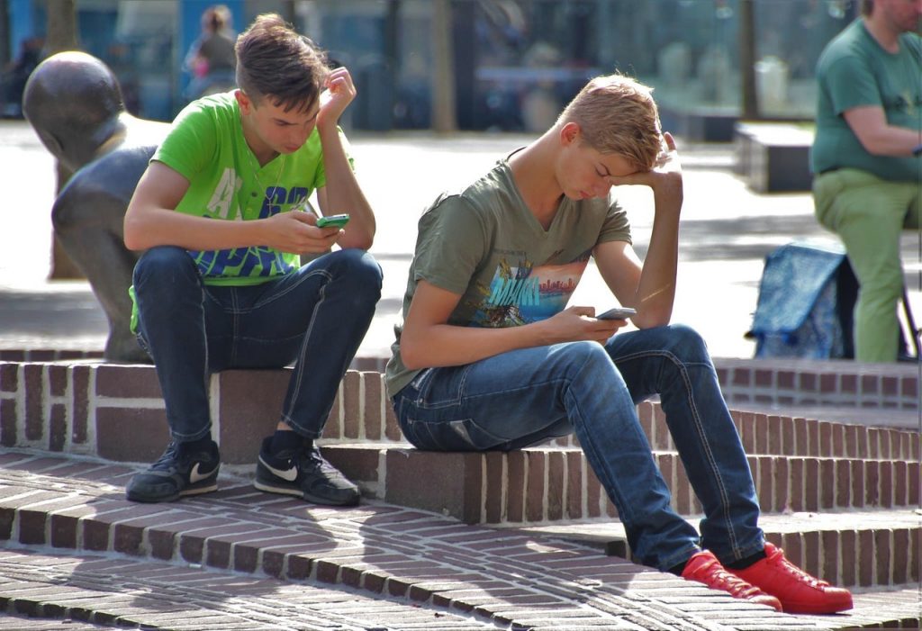 teen boys sitting and looking at their phones
