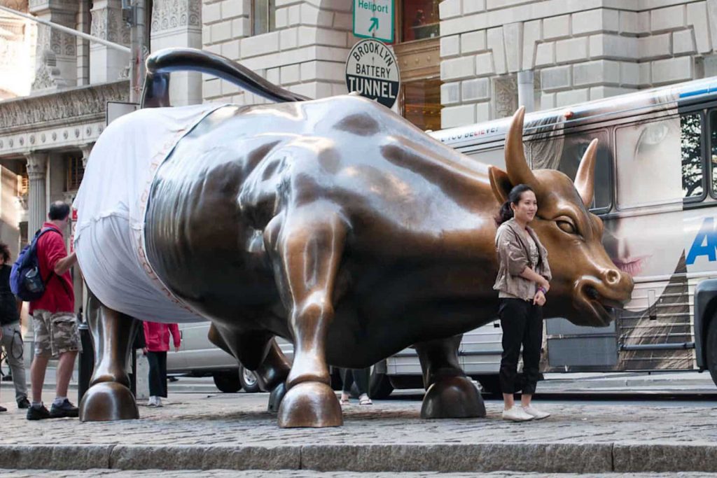 gold toe bull stunt - bull statue - woman taking a picture with a bull statue on the street