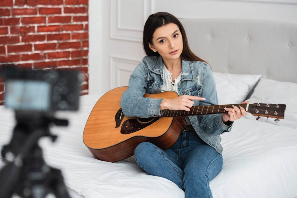 woman playing guitar and filming herself - music promotion